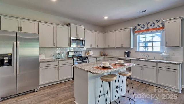 kitchen with stainless steel appliances, wood finished floors, visible vents, and a sink