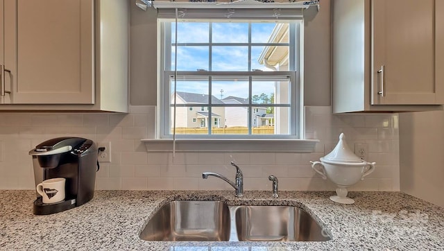 room details featuring decorative backsplash, light stone counters, and a sink