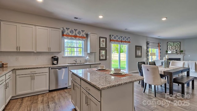 kitchen with light wood finished floors, open floor plan, stainless steel dishwasher, visible vents, and recessed lighting