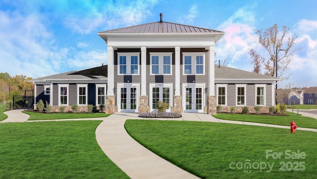 rear view of house featuring french doors, stone siding, and a lawn