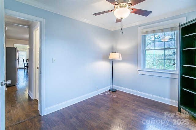 empty room featuring wood finished floors, baseboards, ornamental molding, and a ceiling fan