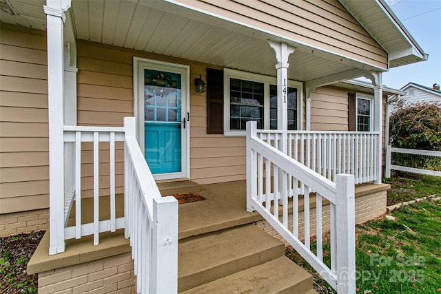 entrance to property featuring covered porch and fence