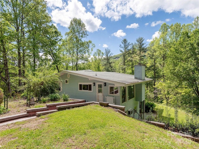 back of property featuring a lawn and a chimney
