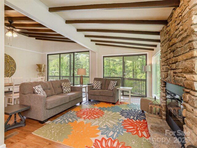 living area with a ceiling fan, wood finished floors, and a fireplace
