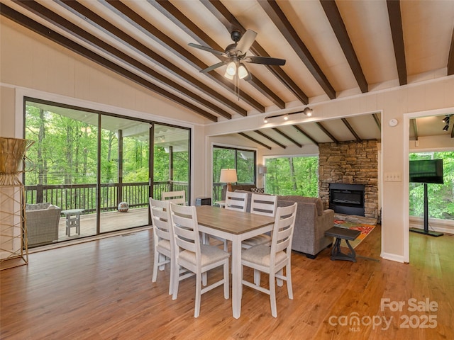 dining space featuring a stone fireplace, light wood-style flooring, and a ceiling fan