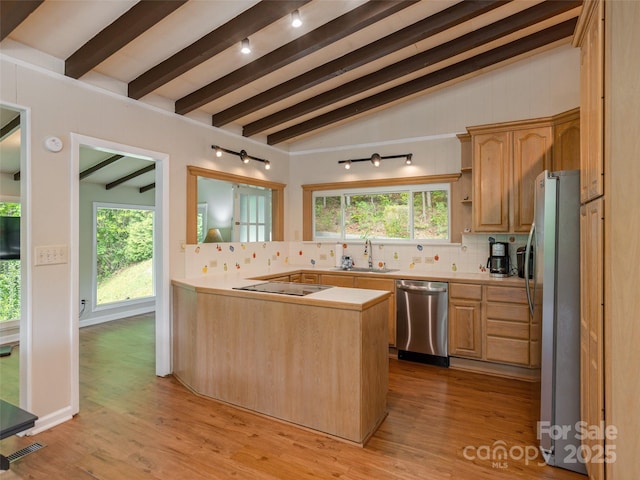 kitchen with appliances with stainless steel finishes, a sink, backsplash, and light countertops