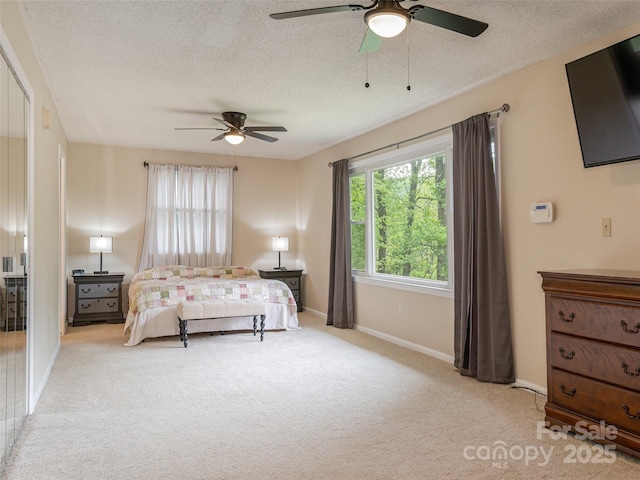 carpeted bedroom featuring a textured ceiling, baseboards, and a ceiling fan