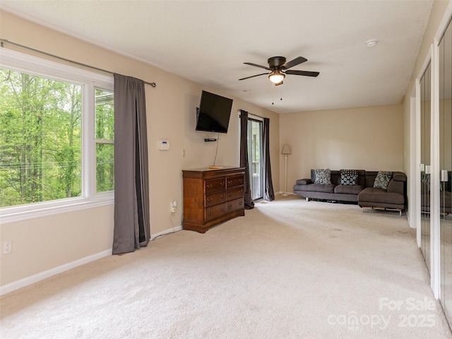 carpeted living room with healthy amount of natural light, ceiling fan, and baseboards