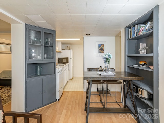 dining room featuring light wood finished floors, built in shelves, and baseboards
