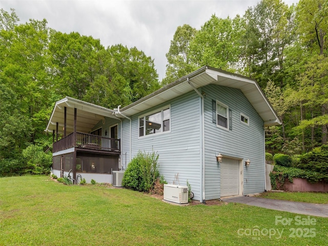 view of side of property featuring central AC, a lawn, a garage, driveway, and a balcony