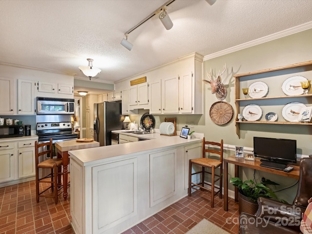 kitchen with black appliances, brick patterned flooring, a peninsula, light countertops, and crown molding