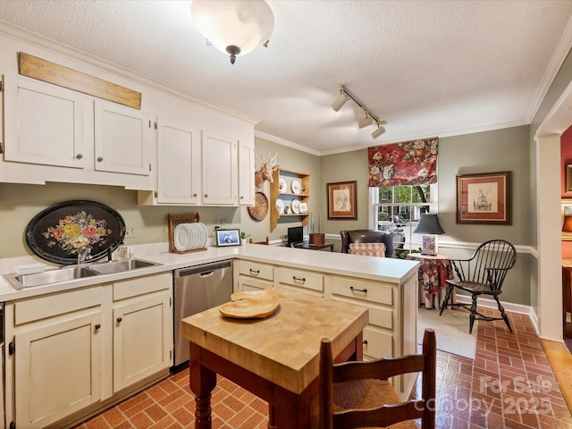 kitchen featuring a peninsula, dishwasher, brick patterned floors, light countertops, and a textured ceiling
