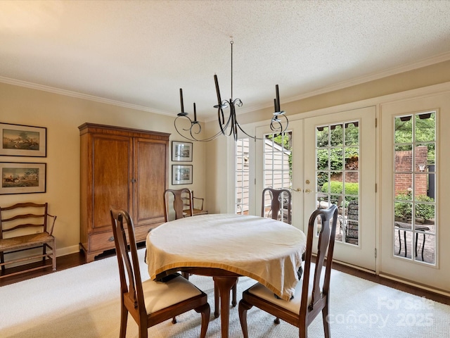 dining room featuring crown molding, healthy amount of natural light, french doors, a textured ceiling, and baseboards