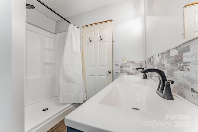 bathroom featuring a textured ceiling, curtained shower, wood finished floors, tasteful backsplash, and vanity