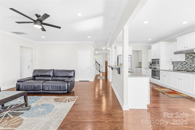 living area with ceiling fan, stairs, baseboards, crown molding, and wood finished floors