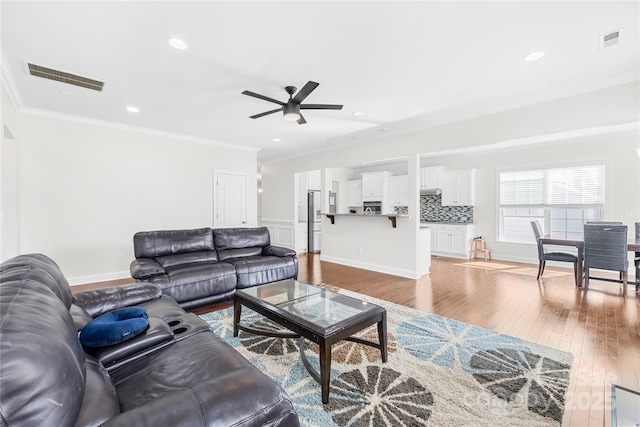 living area featuring ornamental molding, ceiling fan, wood finished floors, and recessed lighting