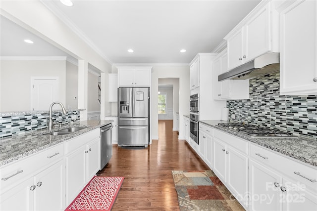 kitchen with stainless steel appliances, a sink, under cabinet range hood, decorative backsplash, and white cabinetry