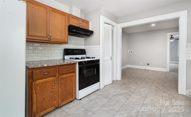 506 7th St SW, Hickory, NC 28602 - kitchen with gas range oven, under cabinet range hood, decorative backsplash, ceiling fan, and freestanding refrigerator