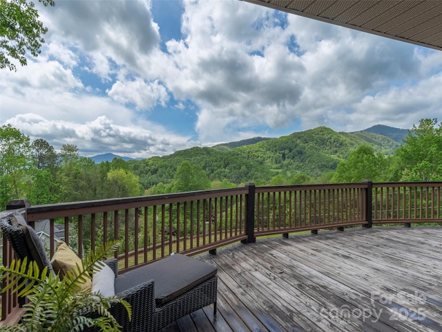 wooden terrace featuring a wooded view and a mountain view