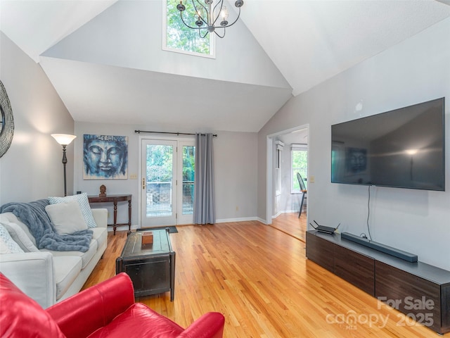 living room featuring a healthy amount of sunlight, light wood-style flooring, high vaulted ceiling, and an inviting chandelier