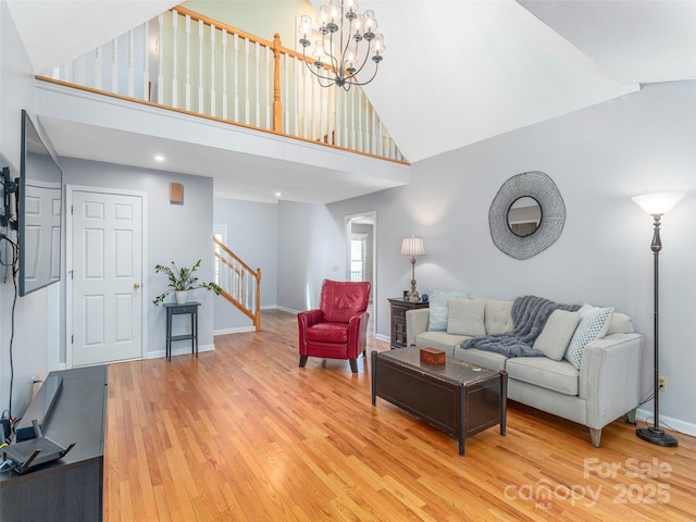 living room with baseboards, stairs, light wood finished floors, and high vaulted ceiling