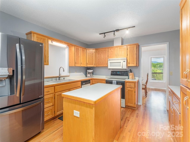 kitchen featuring stainless steel refrigerator with ice dispenser, white microwave, range with electric stovetop, a sink, and light wood finished floors