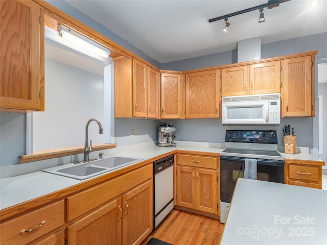 kitchen with a sink, white microwave, dishwashing machine, light countertops, and electric range