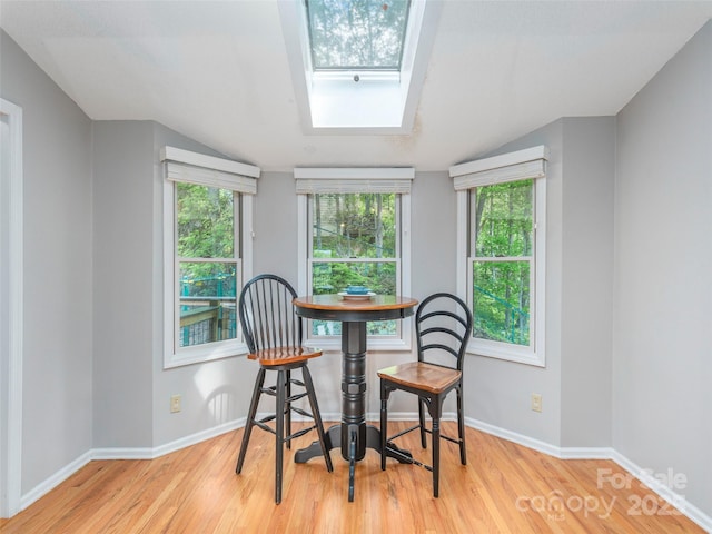 dining area with plenty of natural light, baseboards, wood finished floors, and a skylight