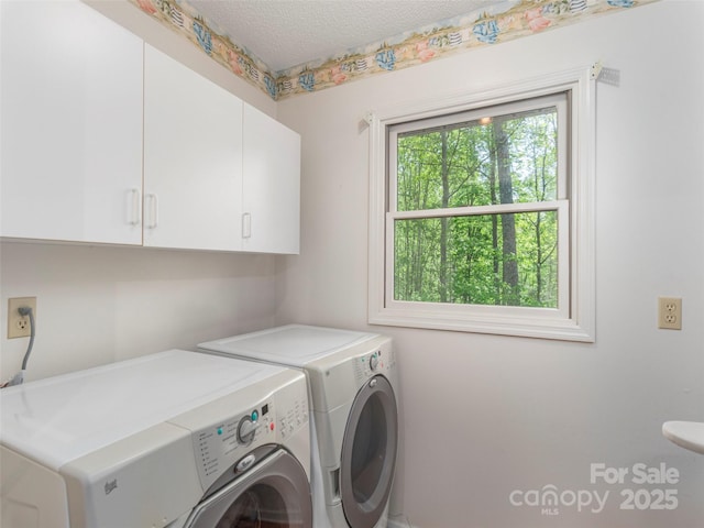 washroom with cabinet space, a textured ceiling, and washer and dryer