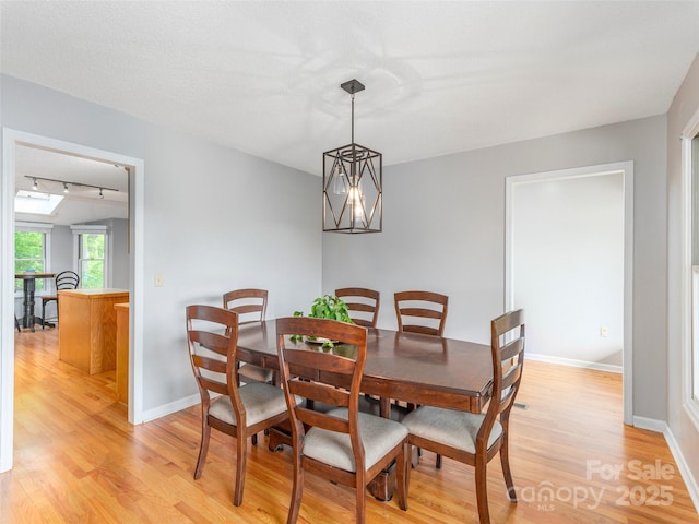 dining area with light wood finished floors, track lighting, and baseboards