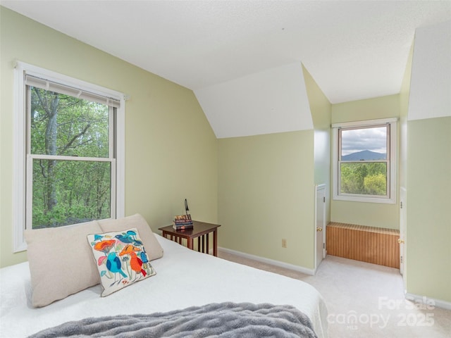 bedroom featuring baseboards, lofted ceiling, and light colored carpet
