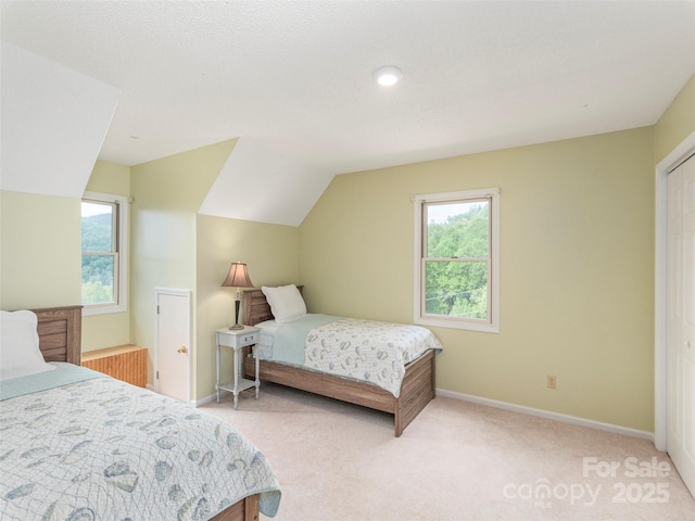 bedroom with lofted ceiling, light carpet, and baseboards