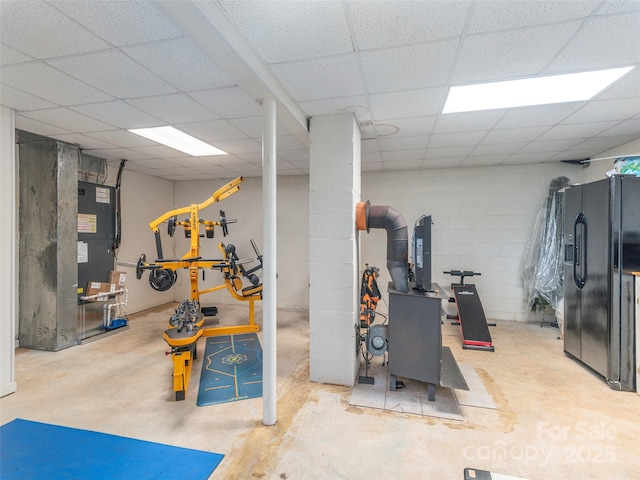 workout room with a paneled ceiling and concrete block wall