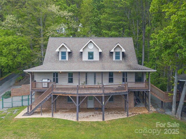 rear view of property featuring covered porch, stairs, fence, and a lawn