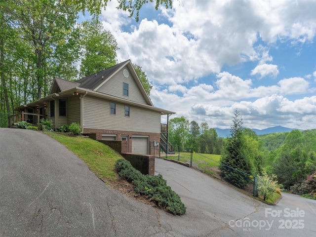 view of side of property featuring brick siding, aphalt driveway, and a garage