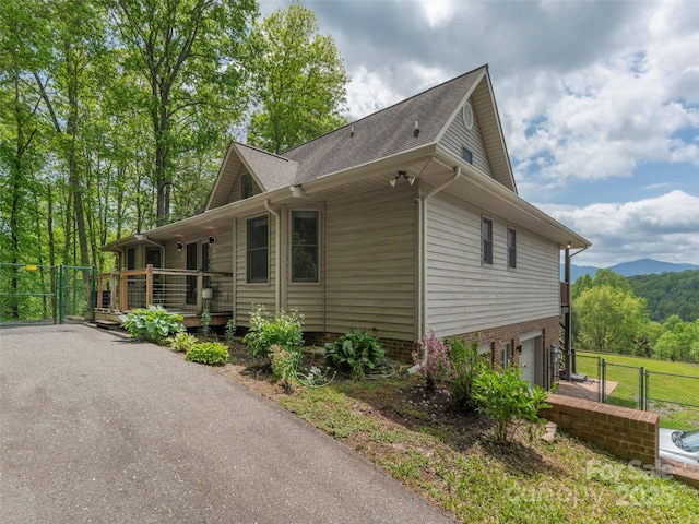 view of home's exterior featuring fence, a garage, and a deck with mountain view