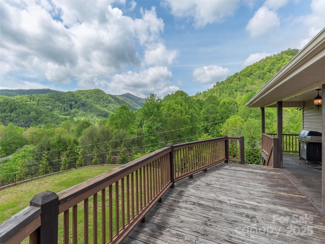 wooden deck featuring a grill and a wooded view