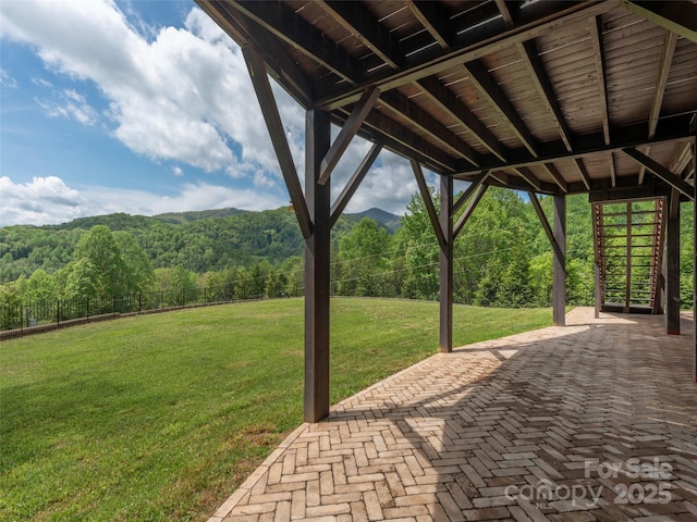 view of patio featuring a wooded view and fence