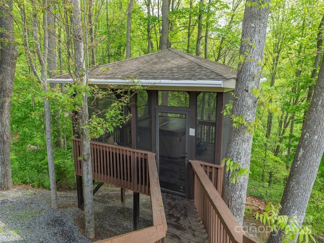view of outdoor structure with a sunroom and a view of trees