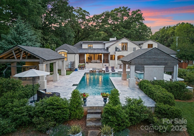 8300 Fairview Rd, Charlotte, NC 28226 - back of house at dusk with a gazebo, a patio area, an outdoor pool, and view of wooded area