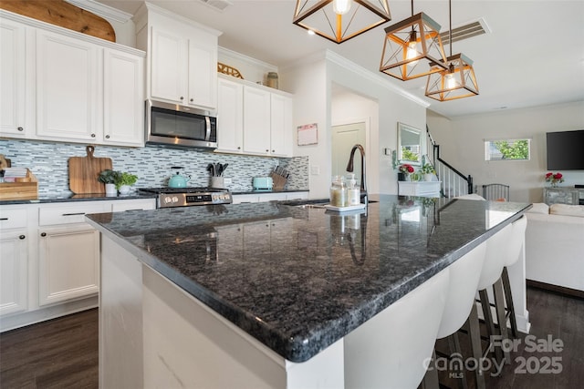 kitchen with stainless steel appliances, a sink, dark wood-style flooring, open floor plan, and white cabinets