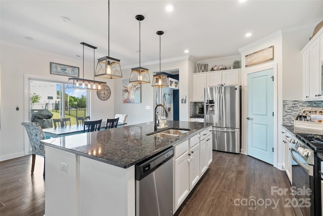 kitchen featuring appliances with stainless steel finishes, a sink, dark wood-type flooring, a center island with sink, and backsplash