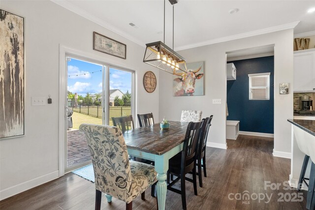 dining area with dark wood finished floors, crown molding, and baseboards