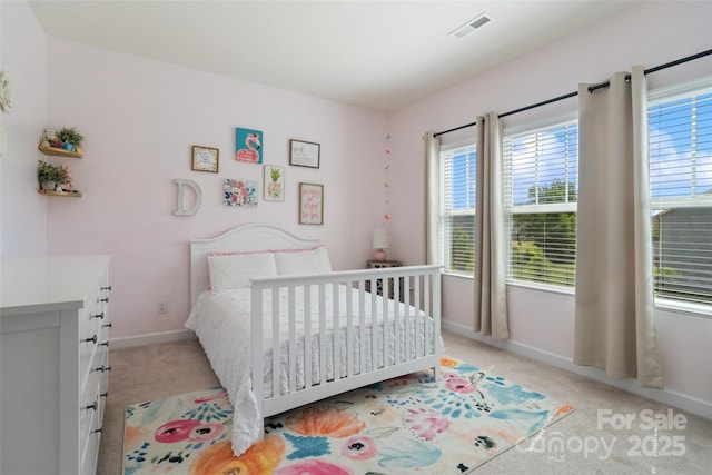 bedroom featuring light carpet, multiple windows, and baseboards