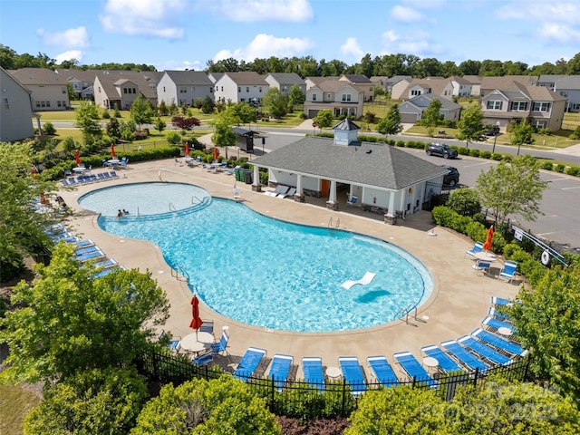 community pool with fence, a residential view, and a patio
