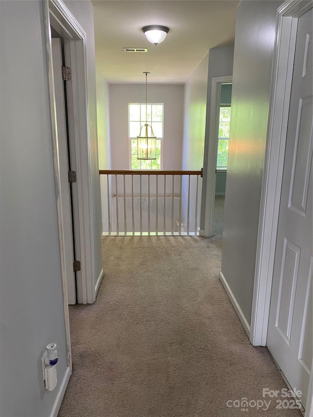 hallway with baseboards, carpet flooring, and visible vents