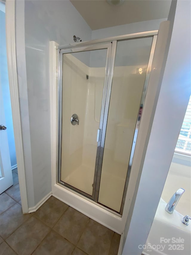bathroom with a stall shower, baseboards, and tile patterned floors