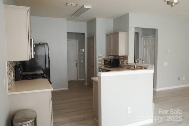 10901 Claude Freeman Dr, Charlotte, NC 28262 - kitchen featuring stainless steel microwave, light wood-type flooring, gas range oven, and backsplash