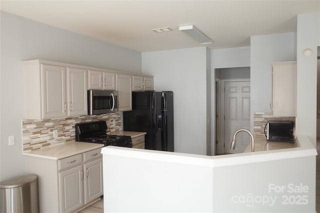 10901 Claude Freeman Dr, Charlotte, NC 28262 - kitchen featuring black appliances, tasteful backsplash, a sink, a peninsula, and light countertops