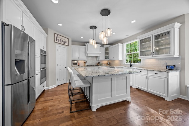 1108 Longwood Ct, Matthews, NC 28104 - kitchen with stainless steel appliances, dark wood-style flooring, white cabinets, a kitchen island, and tasteful backsplash